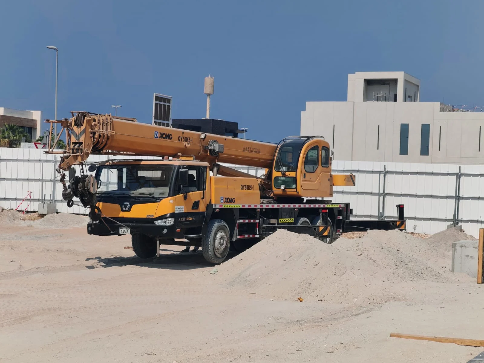 Mobile crane positioned within the prepared villa construction site